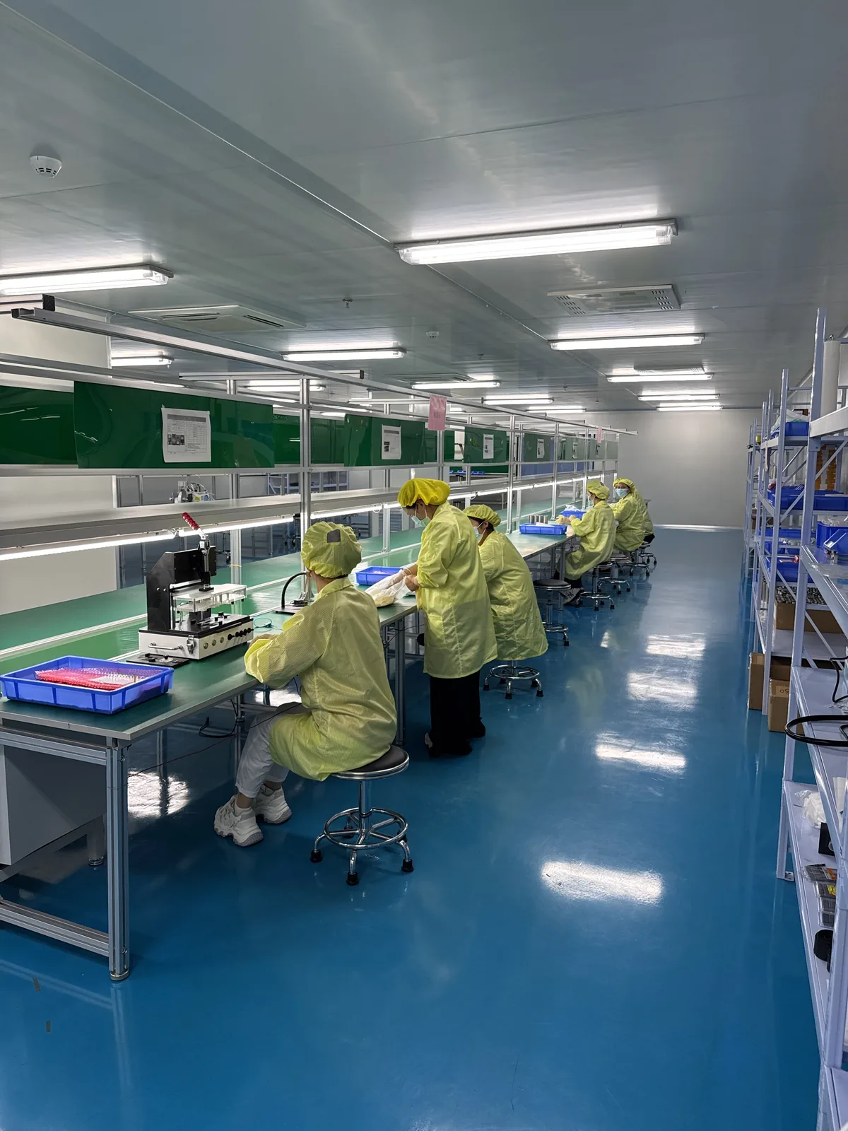 Controlled-environment assembly line with operators in cleanroom garments