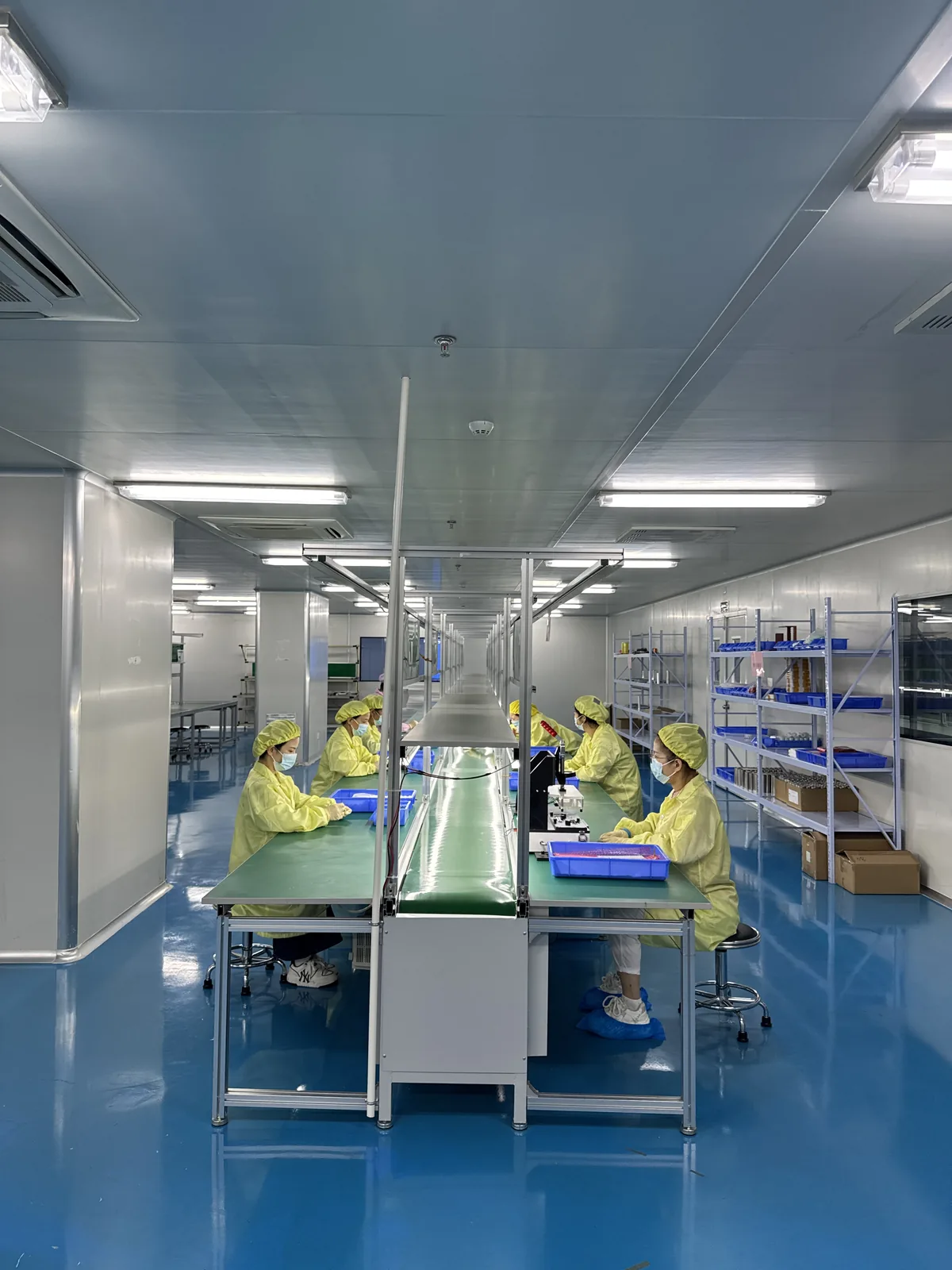 Operators in cleanroom garments working at a production line in a controlled environment