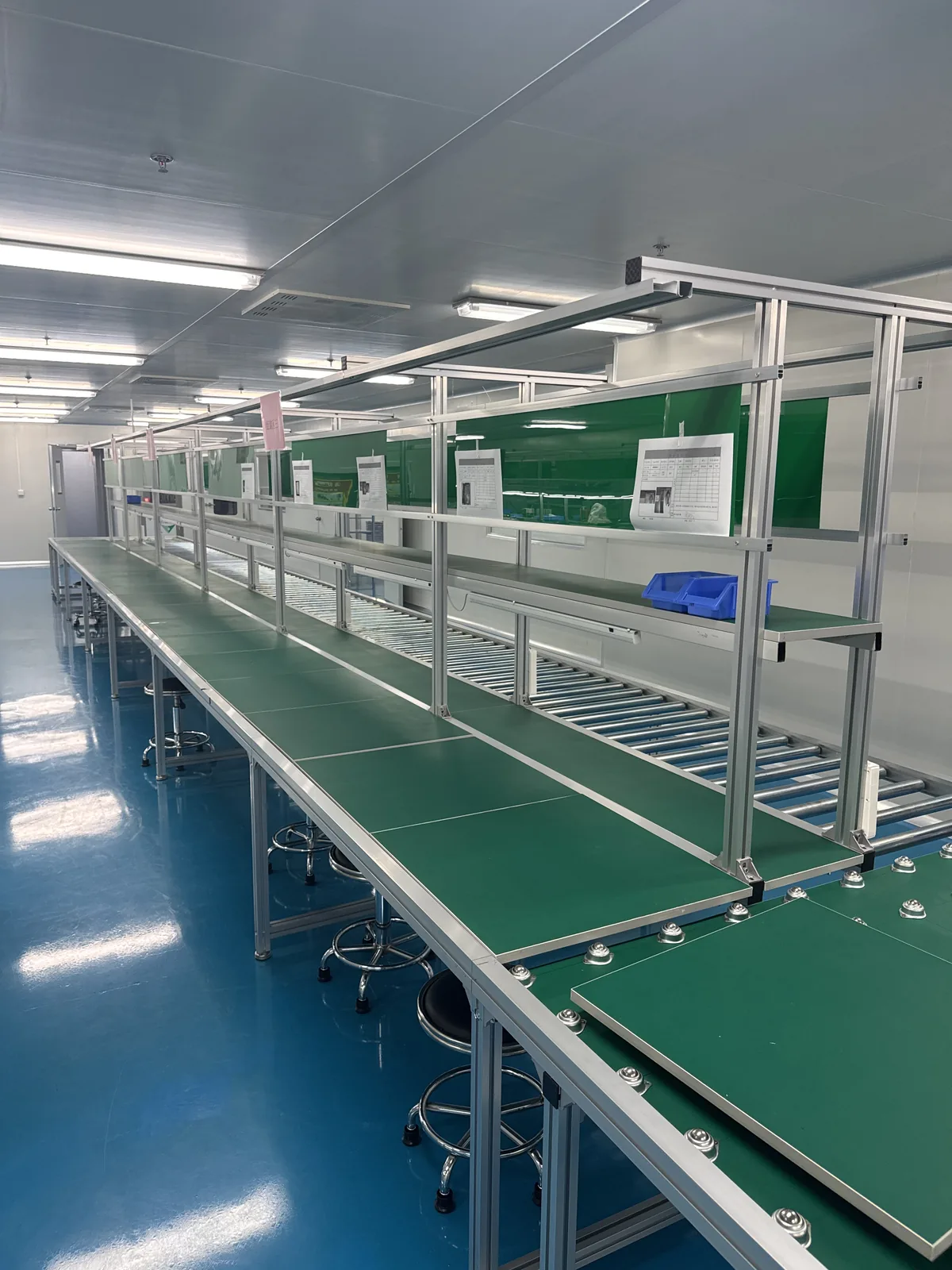 Overhead view along a production line with green work surfaces and side shelving