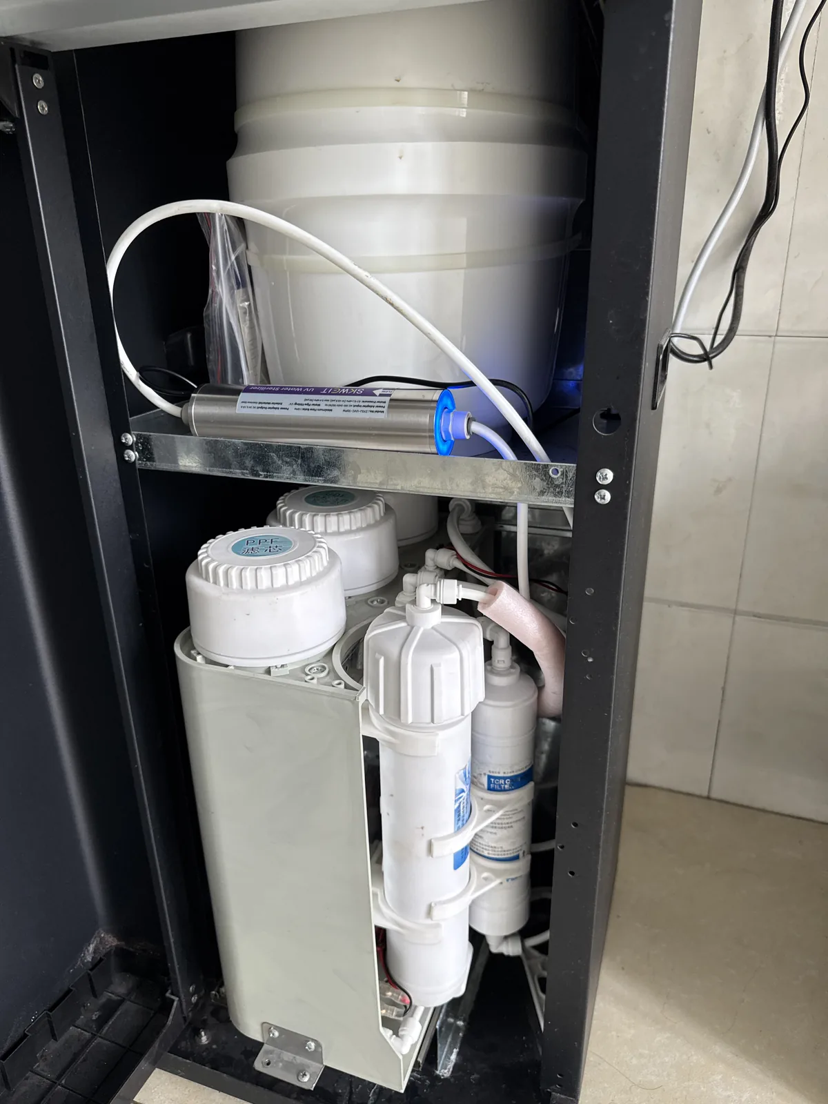In-line UVC sterilizer unit installed inside an under-sink reverse-osmosis system, alongside the filtration stages and the storage tank