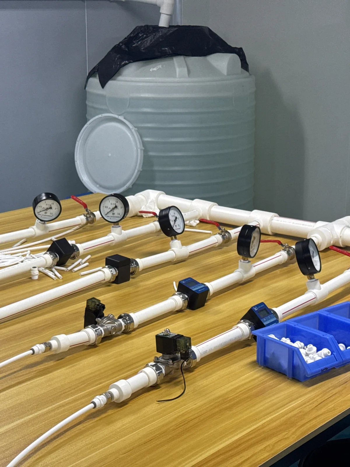 Pressure and flow test rig with gauges, valves and a water reservoir, used to wet-test sterilizer assemblies